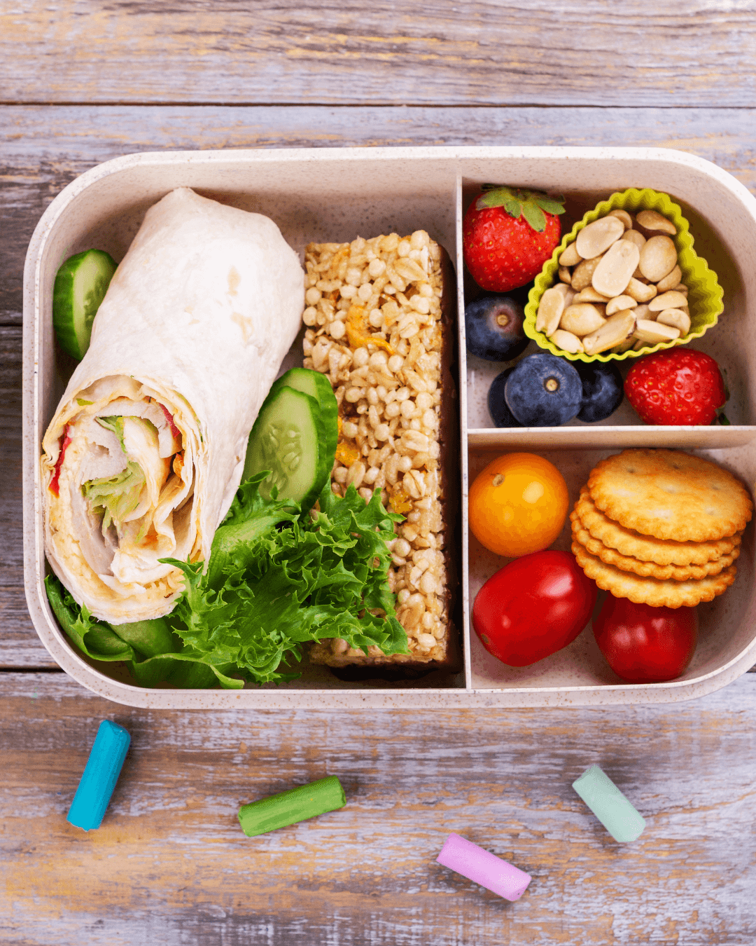 A lunchbox filled with assorted snacks and a wrap.