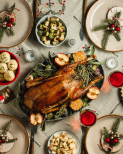 A top-down shot of a table laid with a Christmas turkey, some side dishes and Christmas-themed table decorations